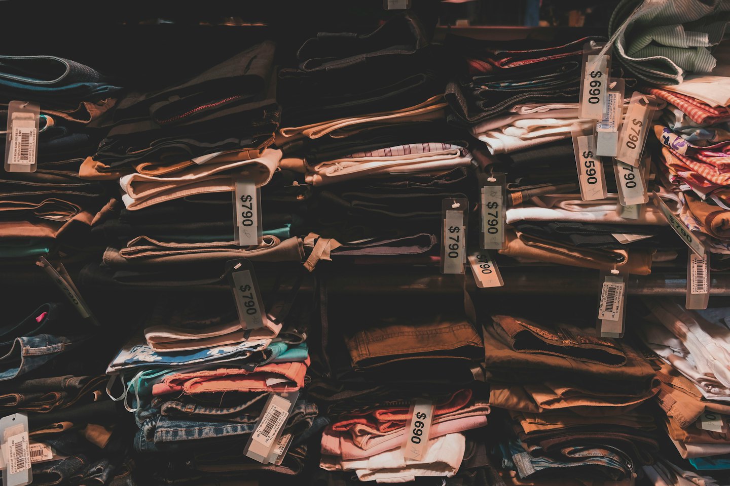 Folded clothes with price tags on retail shelves.